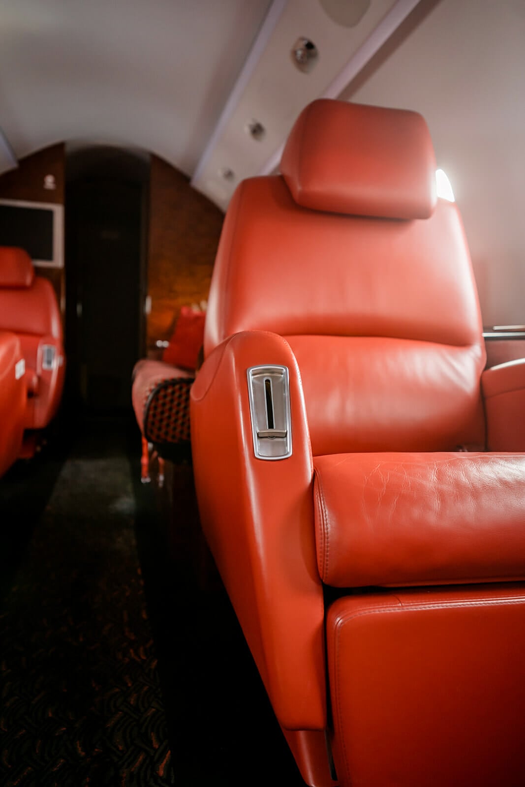 Luxurious red leather seat in a private jet cabin, showcasing sleek design and plush comfort.