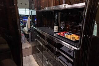 Luxurious aircraft interior featuring a snack tray with wine, fruits, and cheese, alongside a modern cockpit view.