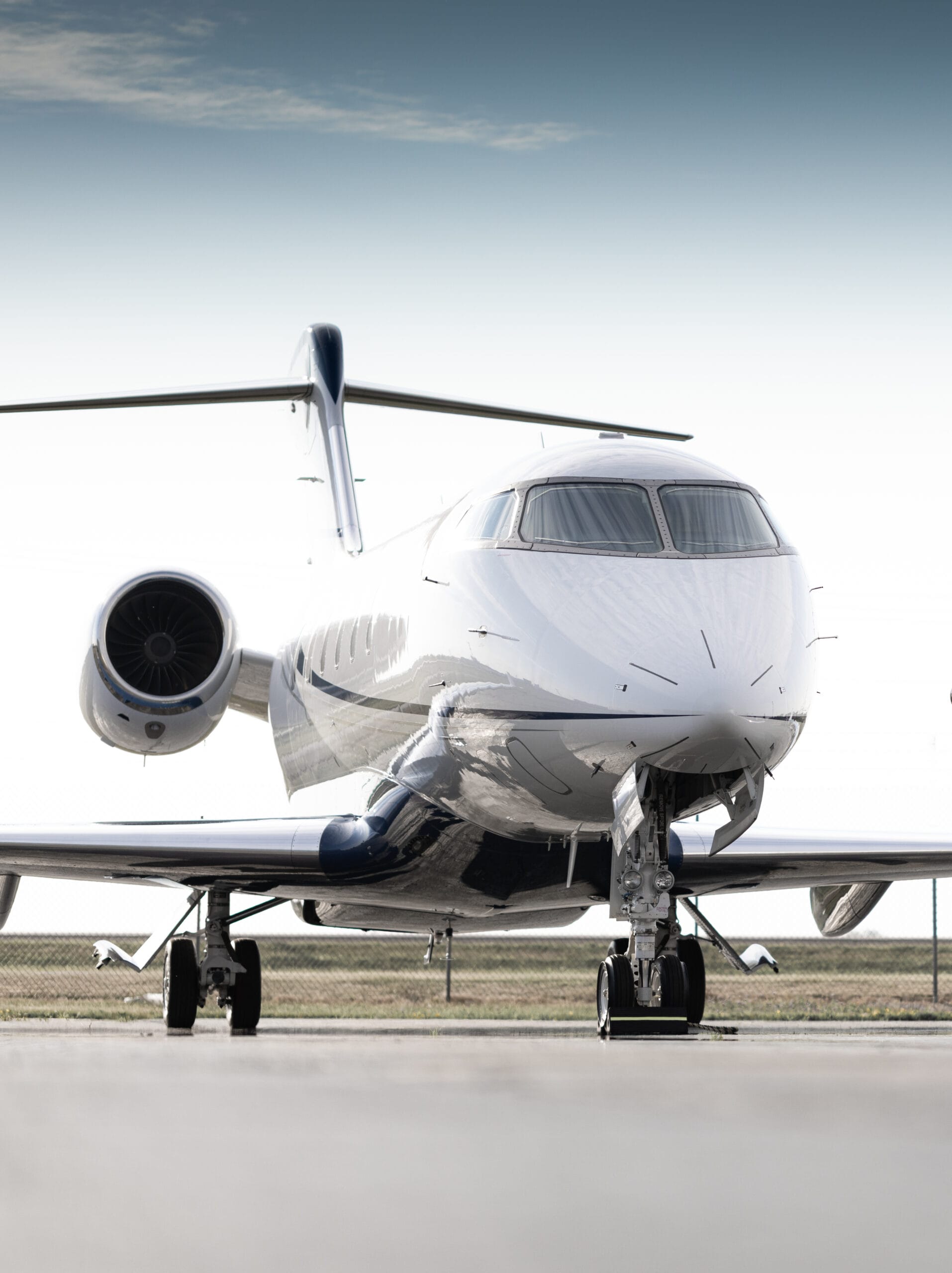 Sleek private jet parked on a runway, showcasing its polished exterior and prominent engines against a clear sky.