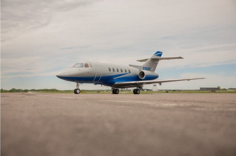 White and blue private jet parked on an airport tarmac.