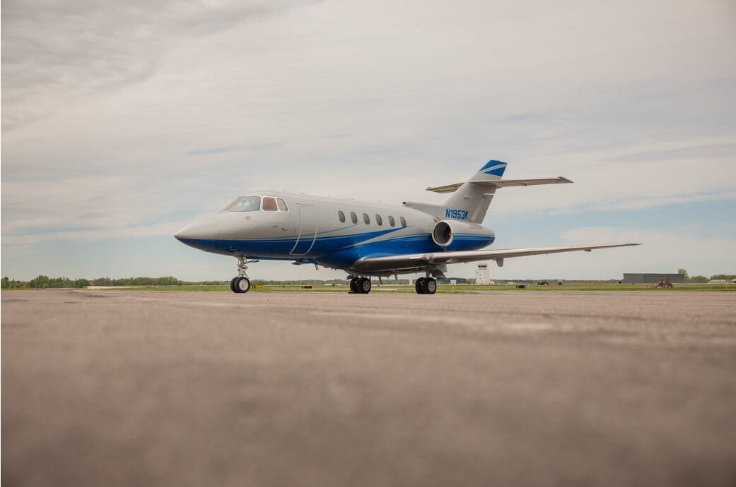 White and blue private jet parked on an airport tarmac.