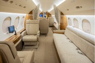 Luxurious private jet interior with plush seating, wood accents, and entertainment screens.