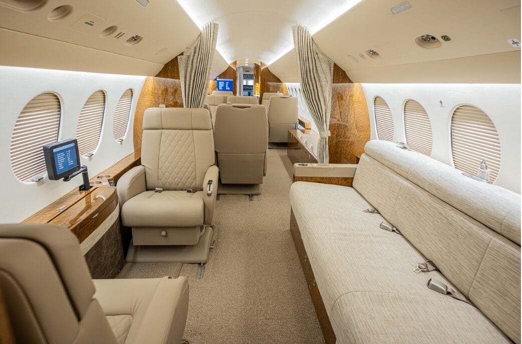 Luxurious private jet interior with plush seating, wood accents, and entertainment screens.