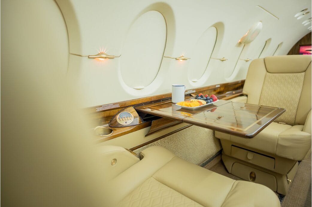 Luxury jet interior with tray table, fruit, and drink.