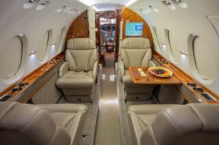 Luxurious private jet interior with plush leather seats, wood trim, and a fruit platter.