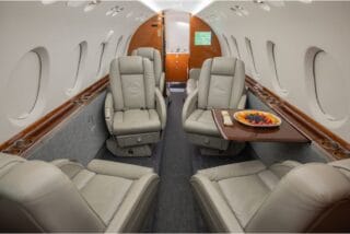 Luxurious private jet interior with plush leather seats and a fruit platter.