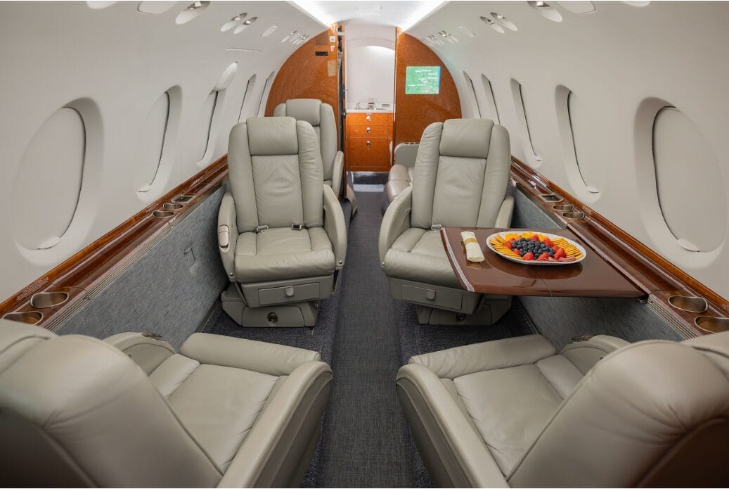 Luxurious private jet interior with plush leather seats and a fruit platter.