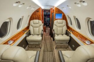Luxurious private jet interior with plush leather seats and wood accents.