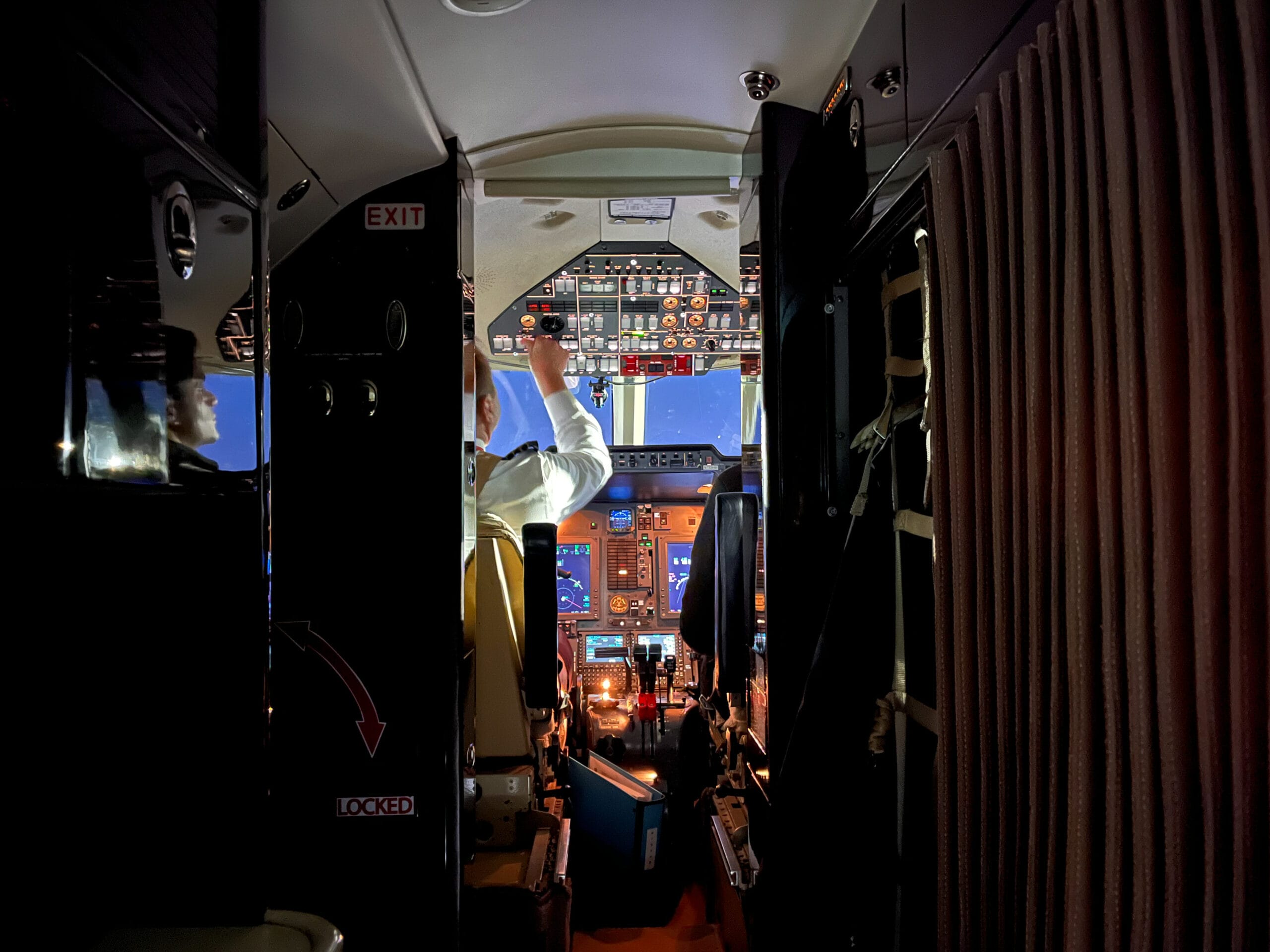 Pilot in cockpit simulator, with screens showing sky and controls.